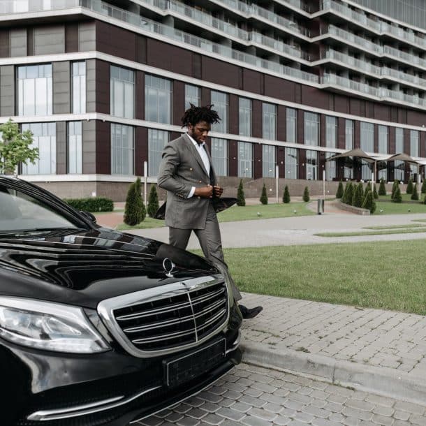 a businessman walking beside a black car