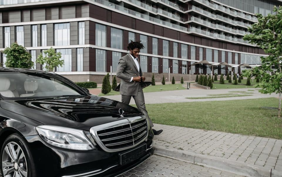 a businessman walking beside a black car