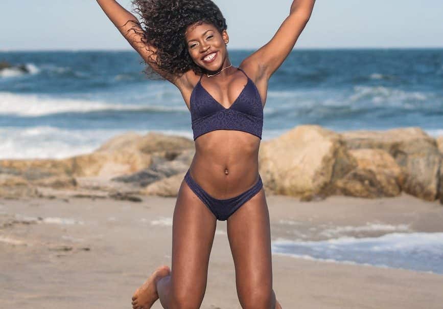 photo of happy woman in two piece bikini jumping on shore